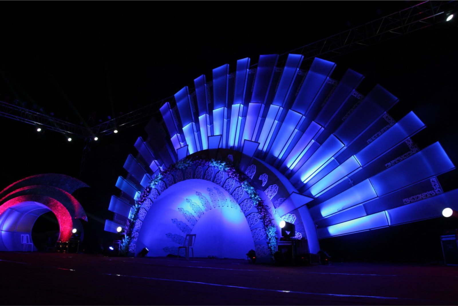 Balloon arch in orange, black, and white colors framing an ITT logo board lit with warm lights